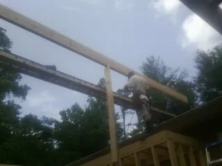 Carpenter setting a ridge beam over a new addition frame — Ice Dam Removal by Roofing Brothers in James Creek