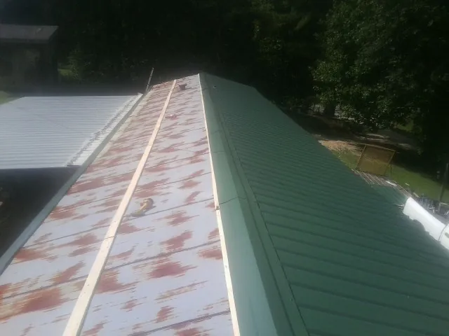 Old rusted panels beside newly installed green metal roofing — Wind Damage Roof Repair by Roofing Brothers in James Creek