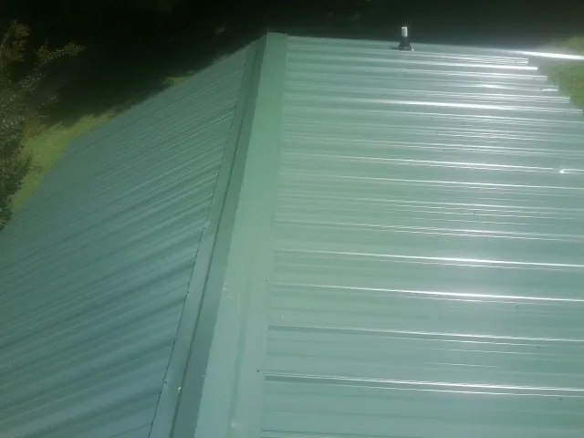New green metal panels meeting at the ridge of a roof — Flat Roof Repair work by our crew in James Creek