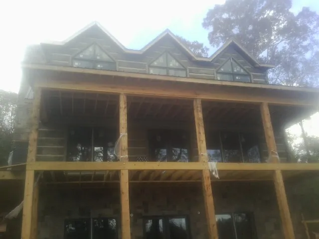 Dormers and porch framing on a large log home under construction — Roof Coating work by our crew in James Creek