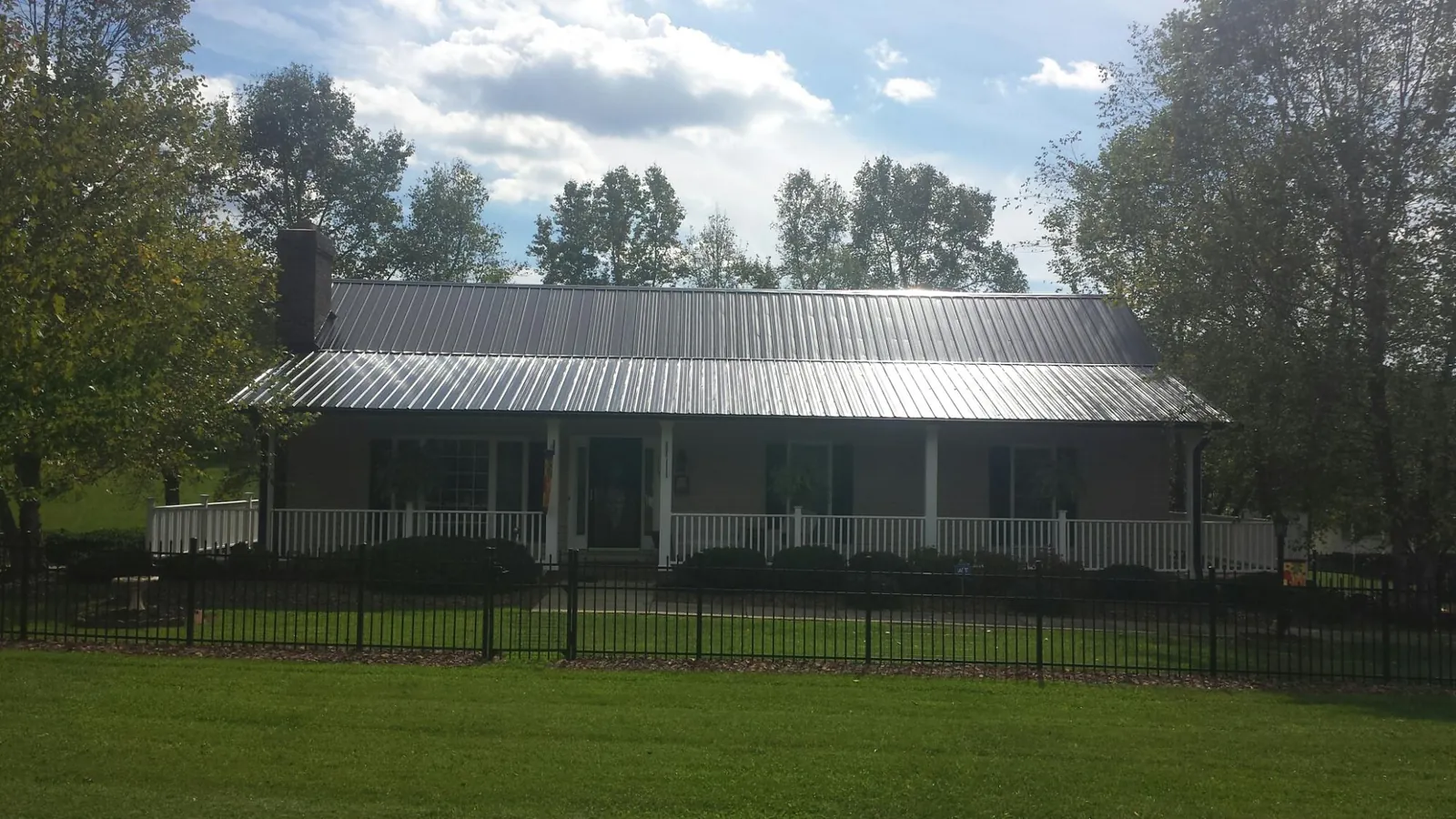 Gray metal roof on a brick ranch with a full width front porch — Gutter Guard Installation work by our crew in James Creek